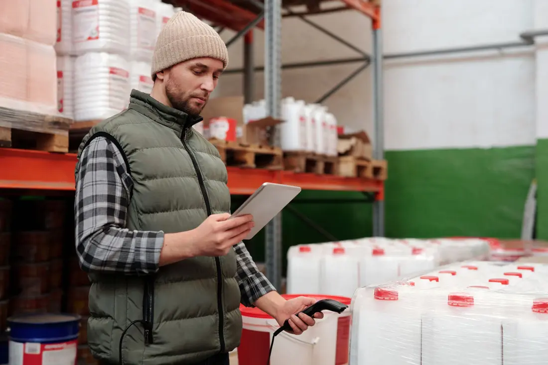 Medewerker in een magazijn scant een emmer met een handscanner en kijkt op zijn tablet